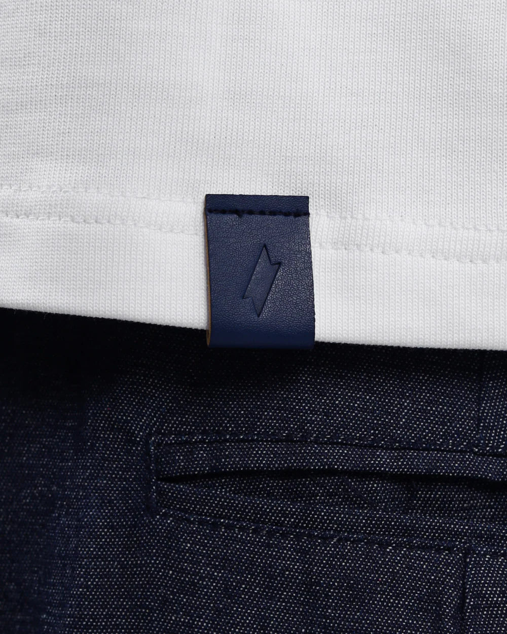 Close-up of a white shirt with a navy blue label on a dark fabric background